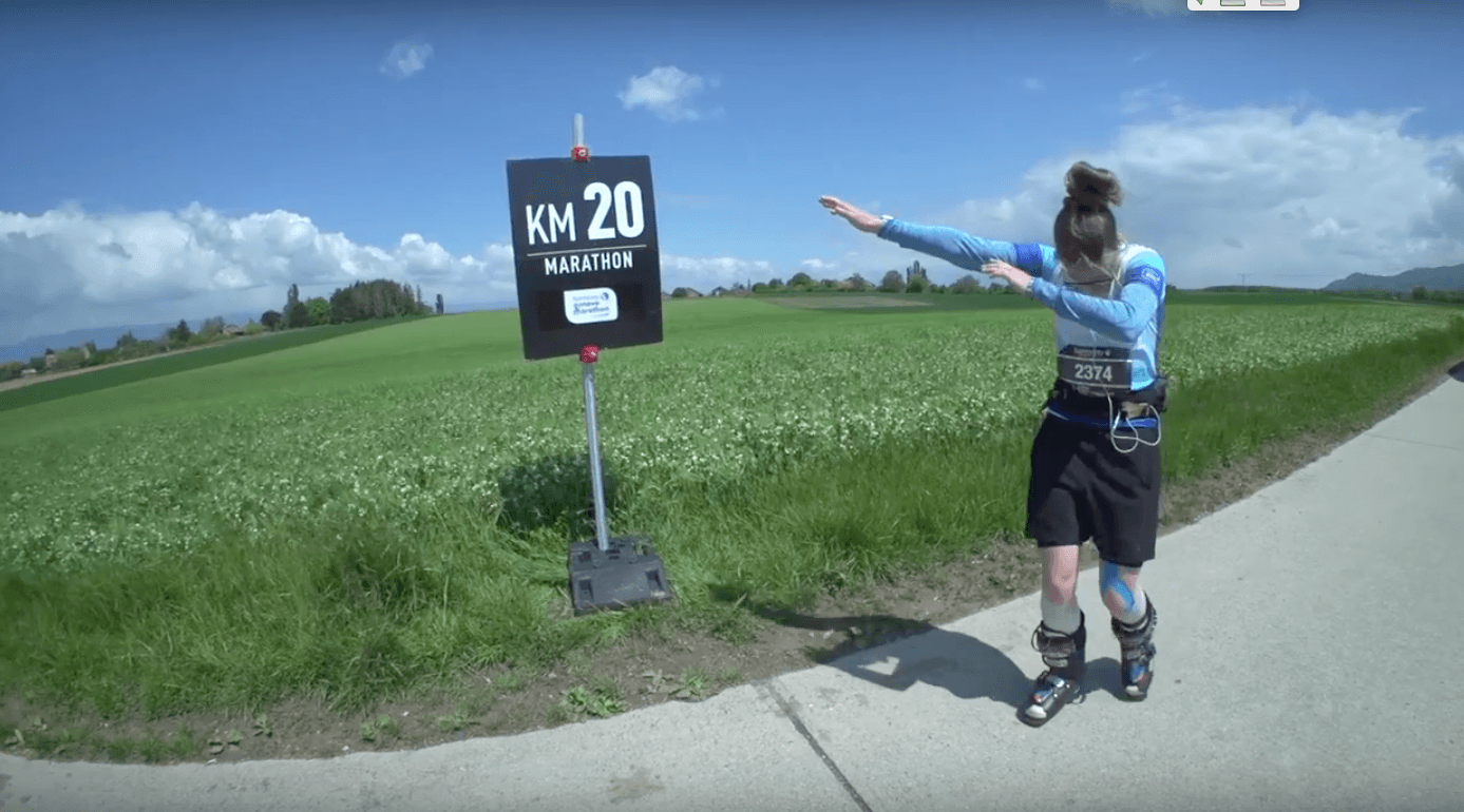 Person running in ski boots in front of KM 20 marathon sign.