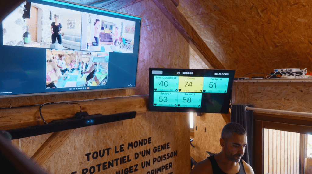Entraînement physique en ligne, caméras et écrans visibles.